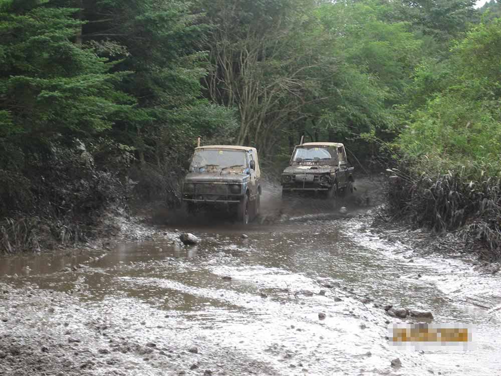 2 Suzuki Jimny trekking through a mud terrain course